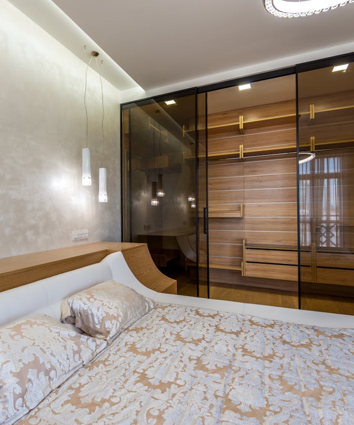 services-05 Luxury interior design of bedroom furnished with comfortable king sized bed and spacious wardrobe closet with glass doors and empty shelves